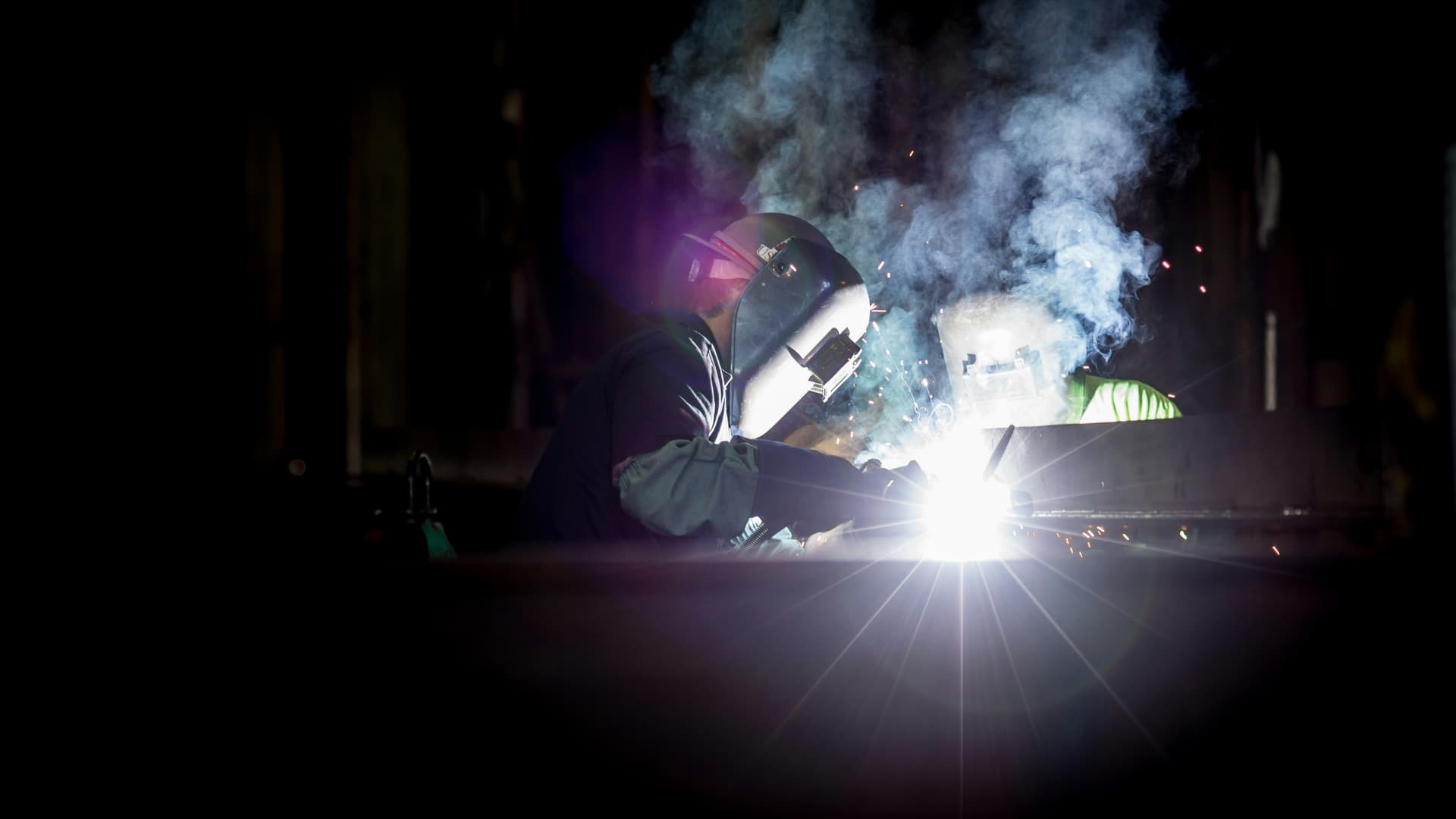 welding in a factory with mask and smoke plume